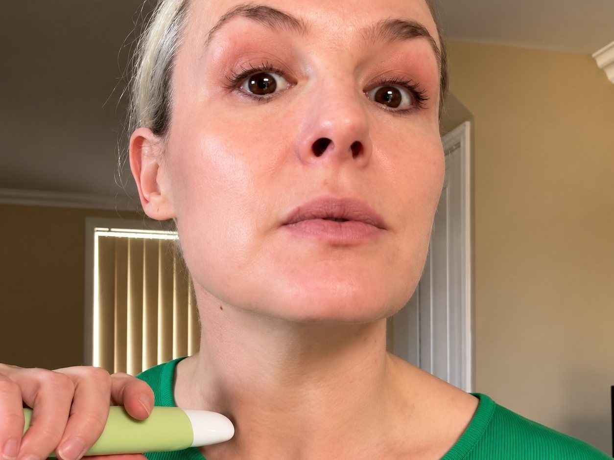 Woman rolling the Collagen Neck Firming Serum up her neck with the cooling tip
