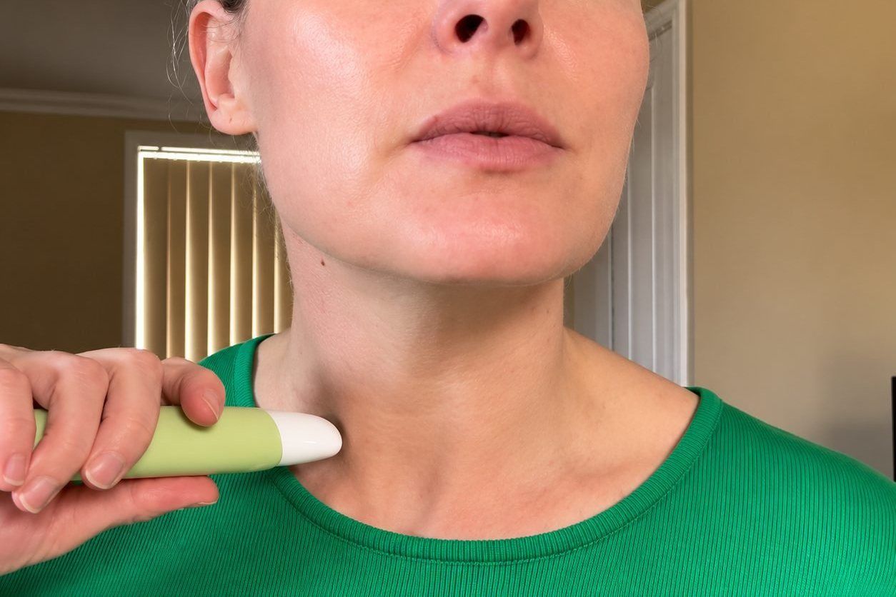 Woman rolling the Collagen Neck Firming Serum upward from her collarbone towards her jaw
